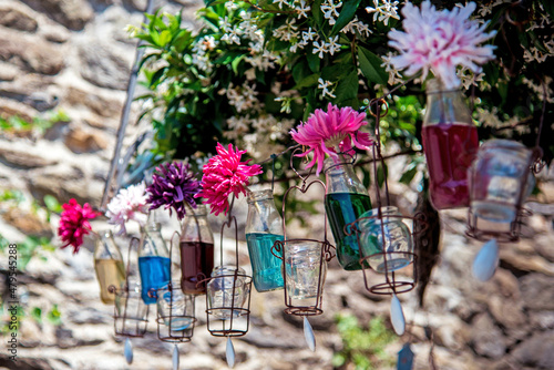 Flowers in jars in the middle of the street against the background of jasmine flowers and a stone wall