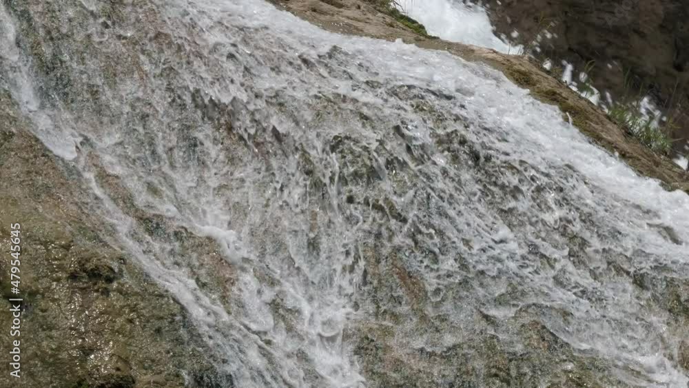 Steady shot of water cascading down the surface of a big rock in a waterfall Steady shot of water cascading down the surface of a big rock in a waterfall