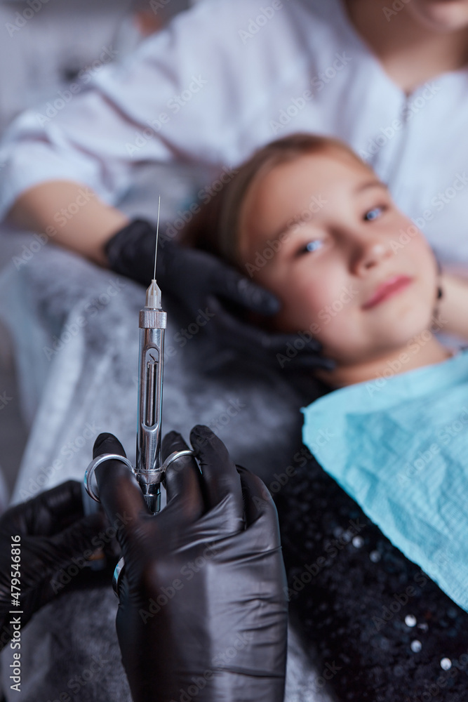 Little girl at dentist office, getting local anesthesia injection into