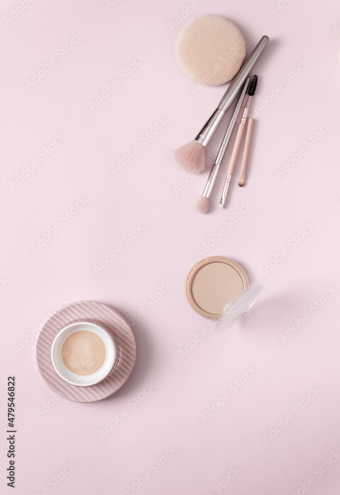 Make up layout, accessories and face powder on pastel pink background. Minimal and luxury make up, cosmetic or beauty salon composition. Flat lay, top view, copy space.