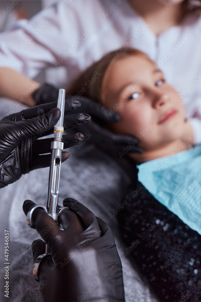 Little girl at dentist office, getting local anesthesia injection into