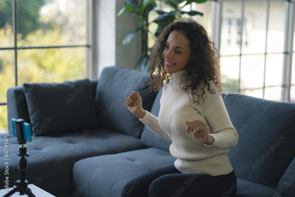 Young African American women live streaming dancing on the sofa through the application from smartphone to social media during the coronavirus outbreak. Young African American women live streaming dancing on the sofa through the application from smartphone to social media during the coronavirus outbreak.