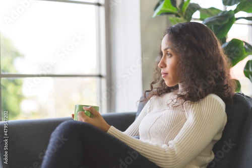 Portrait of beautiful young black woman relaxing and holding coffee mug sit on sofa in holiday at home. business women and freelancers working from home to spread coronavirus covid-19