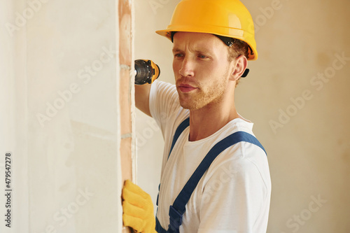 With equipment. Young man working in uniform at construction at daytime