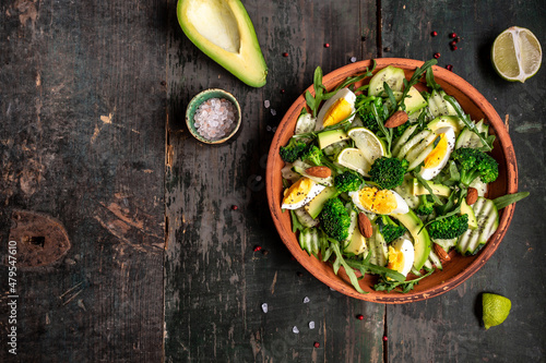 Green salad with avocado, cucumber, broccoli and egg. Healthy organic vegan salat with sliced avocado. Delicious breakfast or snack, Clean eating, dieting, vegan food concept. top view