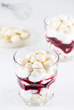 Homemade vegan dessert with meringue, coconut cream and cherries in glasses. Sugar, gluten and lactose free.