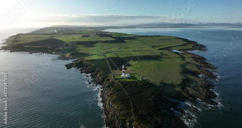 an aerial view of tarbat ness lighthouse on easter ross in the highlands of scotland near inverness showing blue sky and calm seas with the lighthouse dominating the scene and rocks
