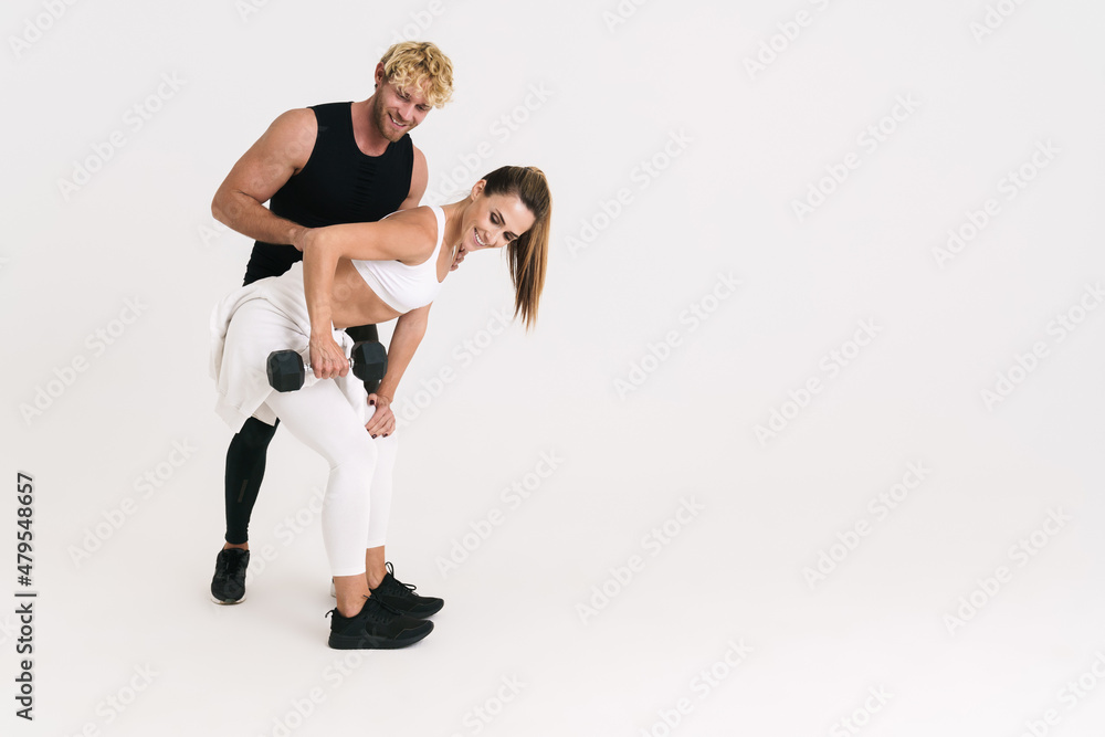 European man and woman in earphones doing exercise with dumbbell