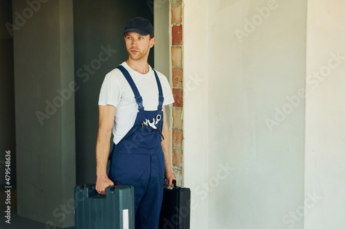 Opening the case. Young man working in uniform at construction at daytime