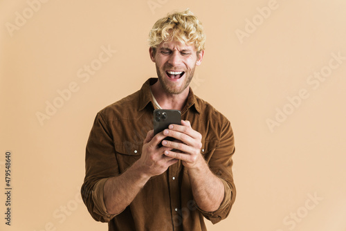 White blonde man wearing shirt laughing and using cellphone