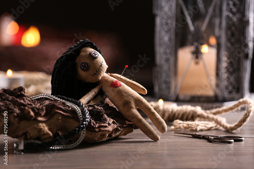 Female voodoo doll with pin in heart and ceremonial items on wooden table Fototapet
