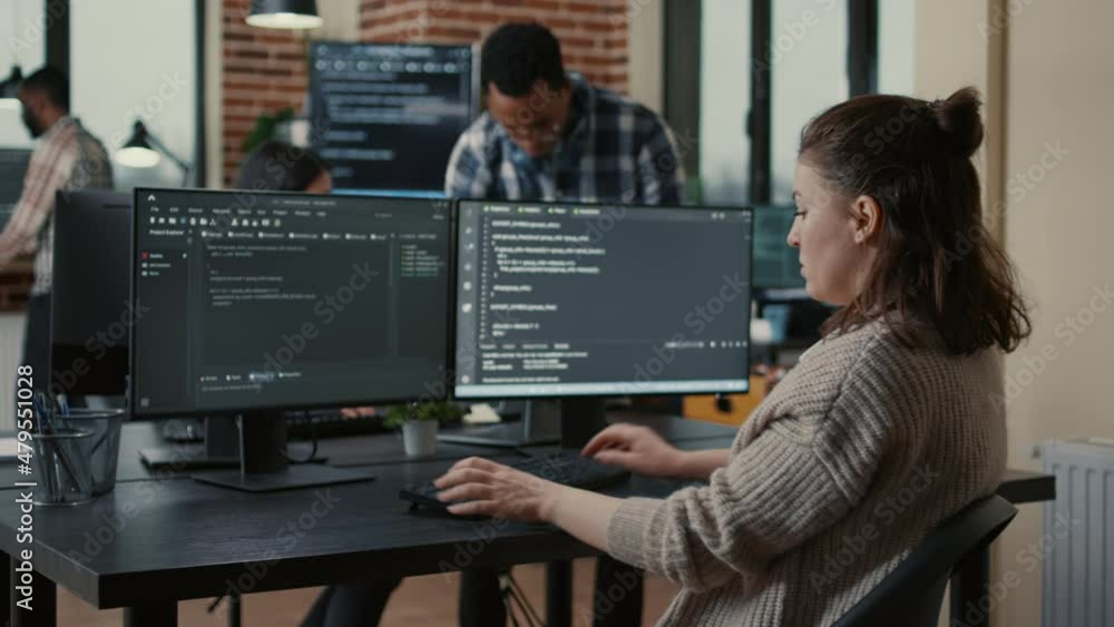 Focused software developer writing code looking at multiple computer ...