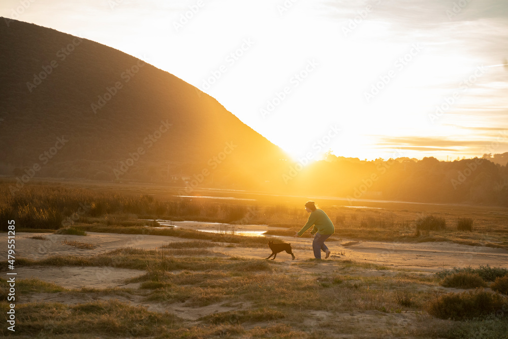 Obraz premium a woman playng with her dog at sunset