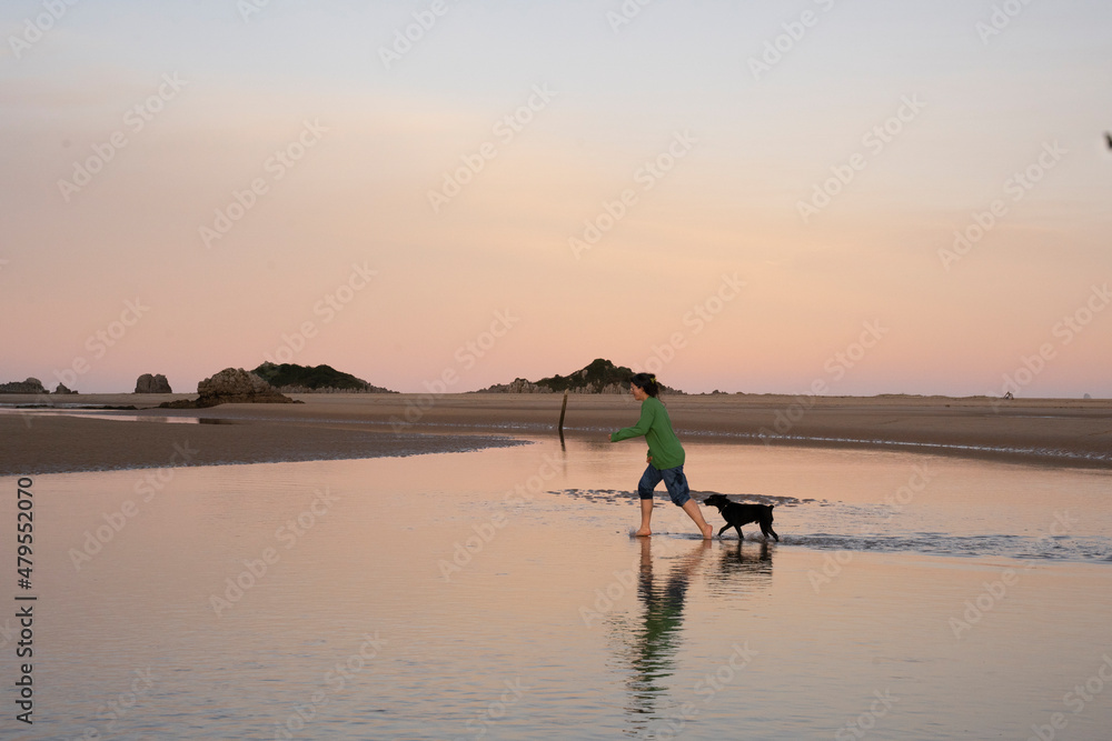 a woman playng with her dog in a lake at sunset