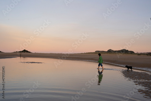 a woman playng with her dog in a lake at sunset
