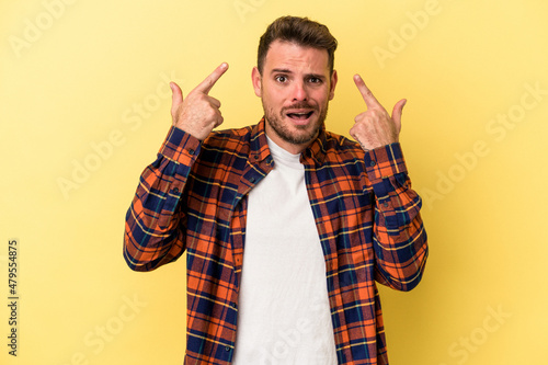 Young caucasian man isolated on yellow background showing a disappointment gesture with forefinger.