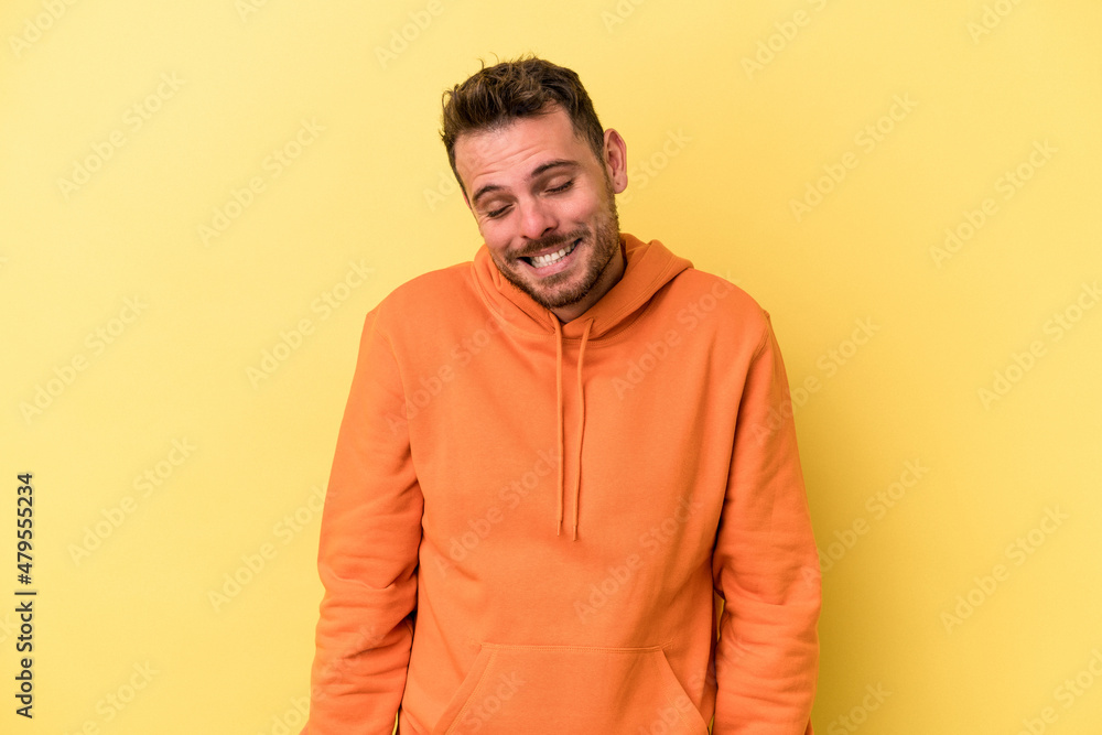 Young caucasian man isolated on yellow background laughs and closes eyes, feels relaxed and happy. Young caucasian man isolated on yellow background laughs and closes eyes, feels relaxed and happy.
