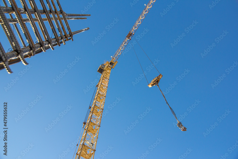 A reinforced steel rebar foundation work and tower crane against the blue sky. Construction. Building construction. A reinforced steel rebar foundation work and tower crane against the blue sky. Construction. Building construction.