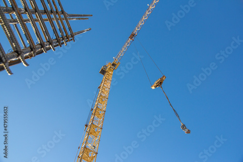 A reinforced steel rebar foundation work and tower crane against the blue sky. Construction. Building construction.