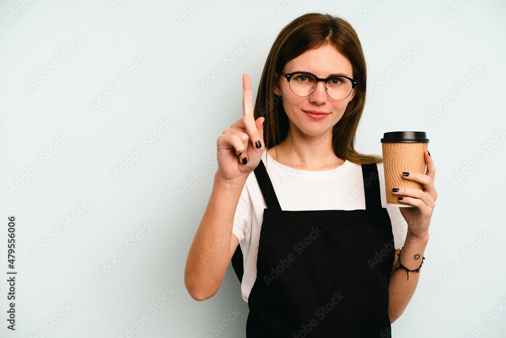 Restaurant waiter woman holding a take away coffee isolated on blue background showing number one with finger. Restaurant waiter woman holding a take away coffee isolated on blue background showing number one with finger.