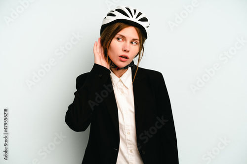 Young business English woman isolated on blue background trying to listening a gossip.