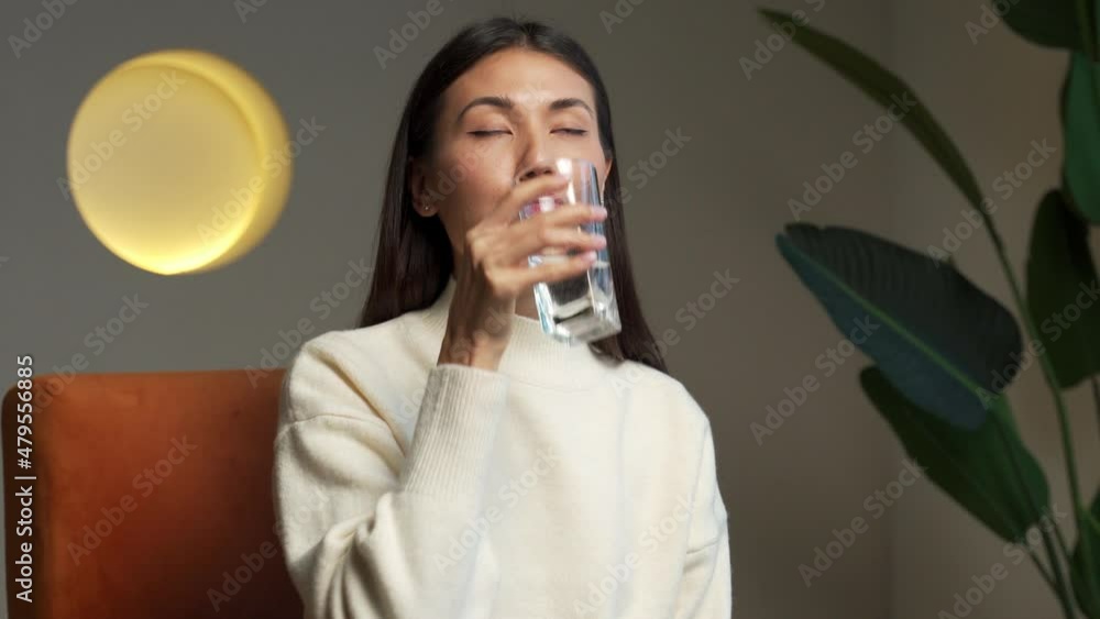 Young asian woman drinking water. Smiling female model holding transparent glass in her hand. Young asian woman drinking water. Smiling female model holding transparent glass in her hand.