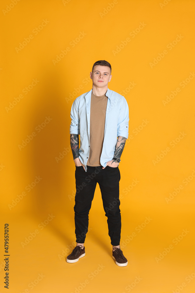 Young man with tattoos on yellow background Young man with tattoos on yellow background