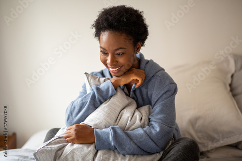beautiful young African American woman sitting in bed and smiling © mimagephotos