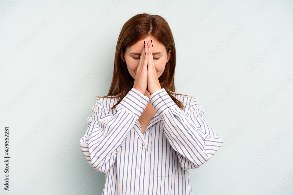 Young English woman isolated on blue background holding hands in pray near mouth, feels confident. Young English woman isolated on blue background holding hands in pray near mouth, feels confident.