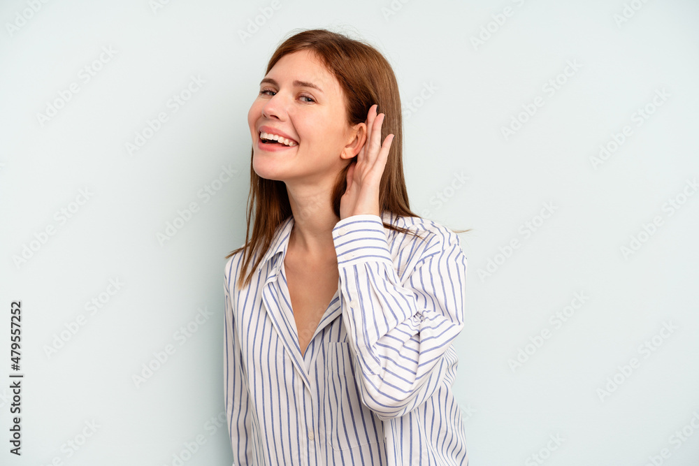 Young English woman isolated on blue background trying to listening a gossip. Young English woman isolated on blue background trying to listening a gossip.
