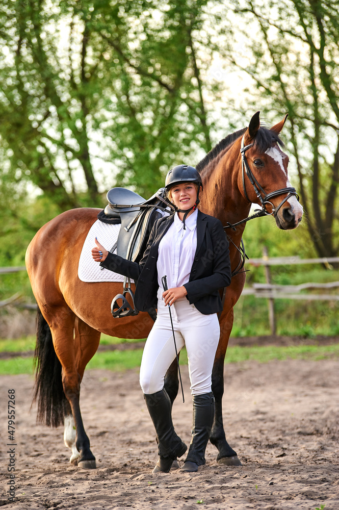 Beautiful horse rider girl stands near a horse on a farm
Beautiful horse rider girl stands near a horse on a farm