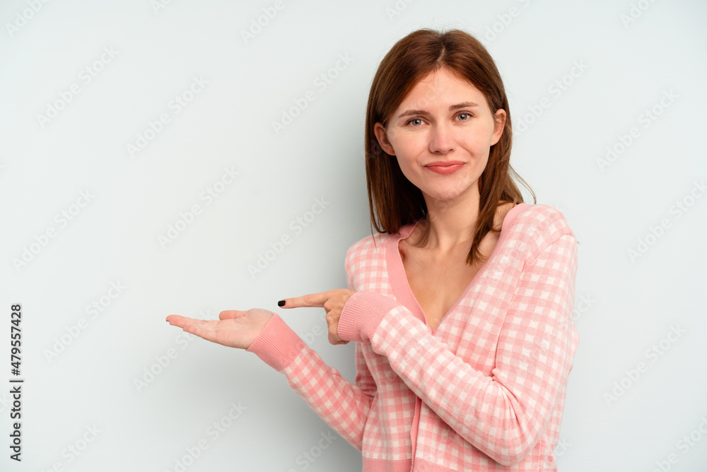 Young English woman isolated on blue background excited holding a copy space on palm. Young English woman isolated on blue background excited holding a copy space on palm.