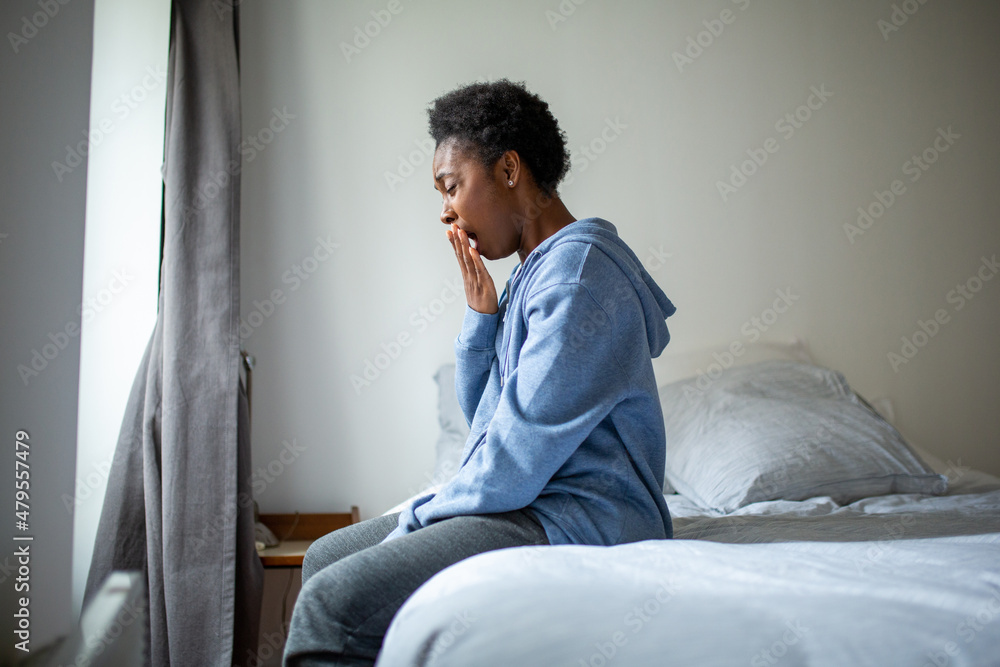Profile of young african American woman waking up in bed and yawning