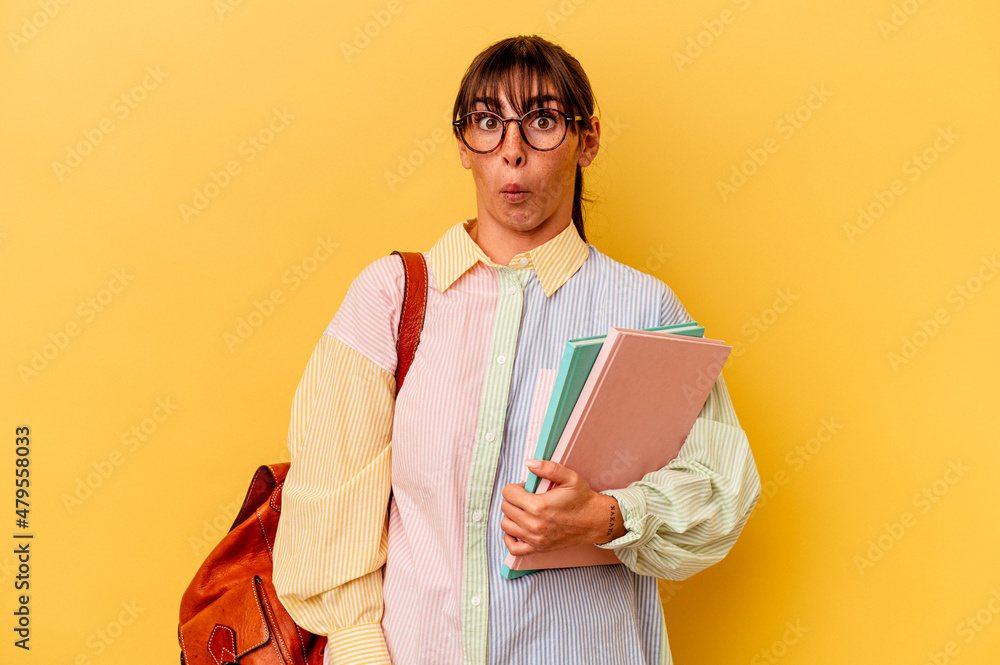 Fototapeta premium Young student Argentinian woman isolated on yellow background shrugs shoulders and open eyes confused.