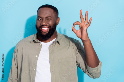 Photo of young cheerful african guy wink eye promoter approve good ads isolated over blue color background