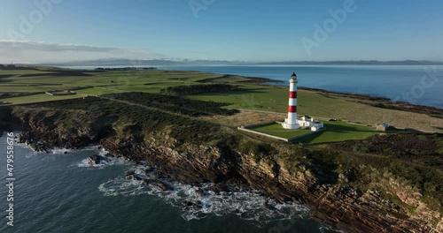 an aerial view of tarbat ness lighthouse on easter ross in the highlands of scotland near inverness showing blue sky and calm seas with the lighthouse dominating the scene and rocks photo