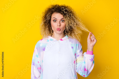 Portrait of attractive amazed funny girly wavy-haired girl pout lips touching hair isolated over bright yellow color background