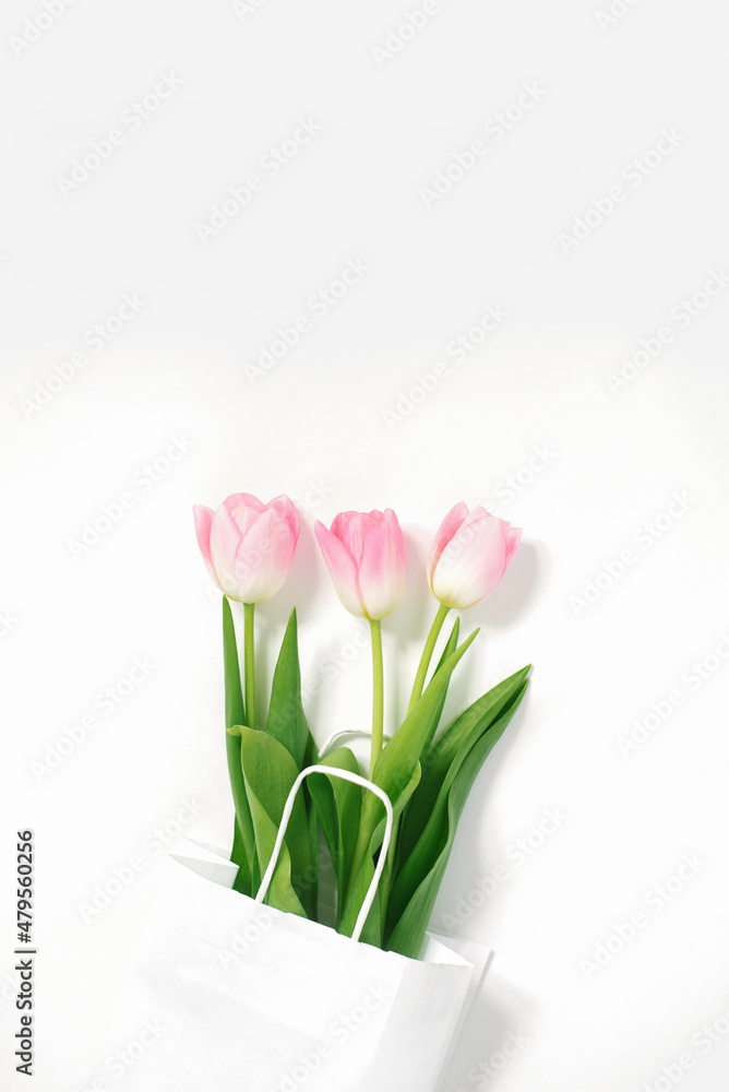 Flat lay composition with pink tulips in paper bag on white background