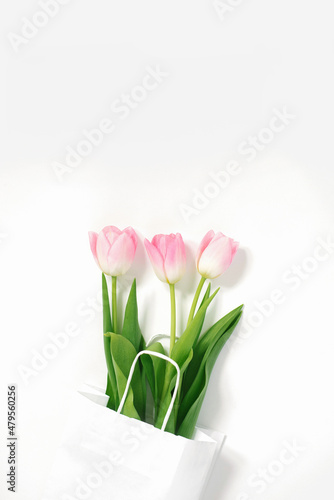 Fototapeta Naklejka Na Ścianę i Meble -  Flat lay composition with pink tulips in paper bag on white background