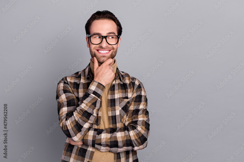Photo of cute thoughtful man wear plaid shirt spectacles looking empty space arm chin isolated grey color background Photo of cute thoughtful man wear plaid shirt spectacles looking empty space arm chin isolated grey color background