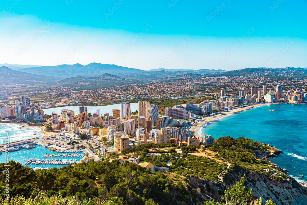 Panorama of Calpe, province of Alicante, Costa Blanca in summer. Harbor with sea ships, yachts. View from the rock Penon de Ifach. Landscape outside the city. Travel, hiking, vacation at sea concept.