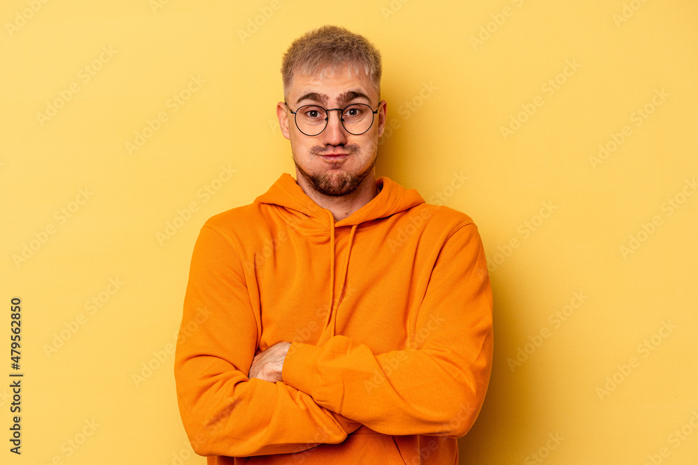 Young caucasian man isolated on yellow background blows cheeks, has tired expression. Facial expression concept. Young caucasian man isolated on yellow background blows cheeks, has tired expression. Facial expression concept.
