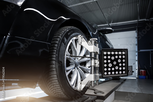 CLose-up car wheel indoors service maintenance repair center against laser sensor equipment diagnostics and 3d wheel alignment. Vehicle inside garage workshop for auto camber toe check fixing work