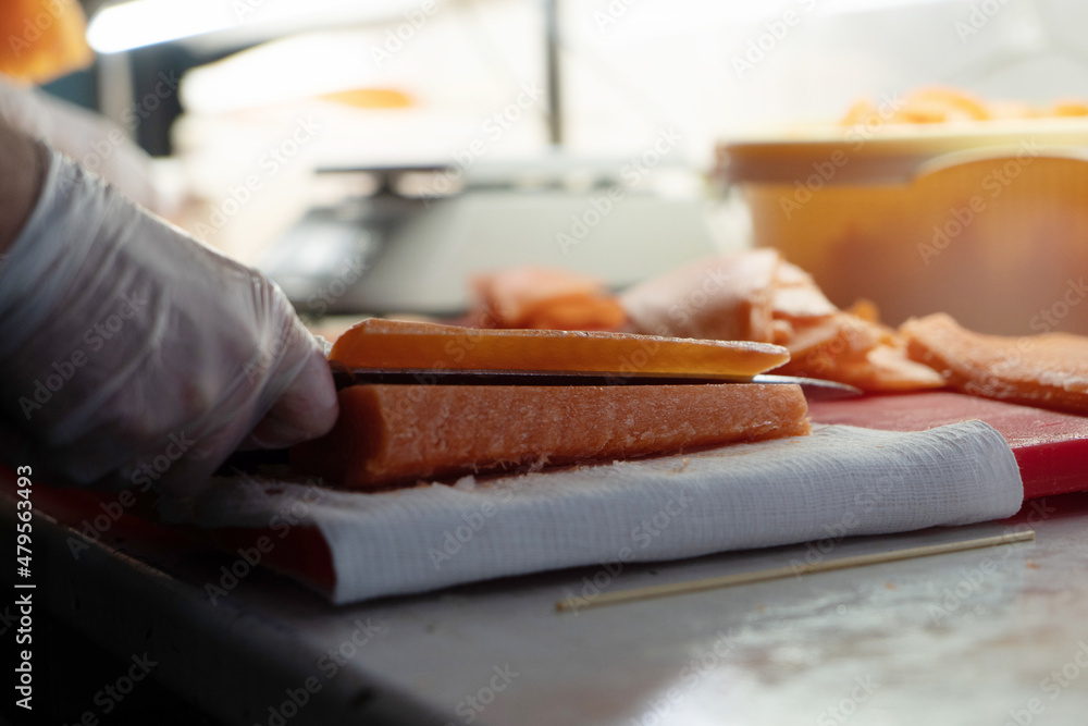 chef cuts a red fish with a knife on a cutting board in a restaurant for a beautiful presentation chef cuts a red fish with a knife on a cutting board in a restaurant for a beautiful presentation