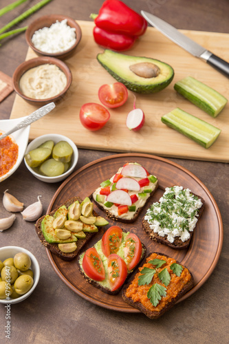 Healthy fast food. Different homemade vegan, vegetarian sandwiches with vegetables and greens on bread on plate on kitchen