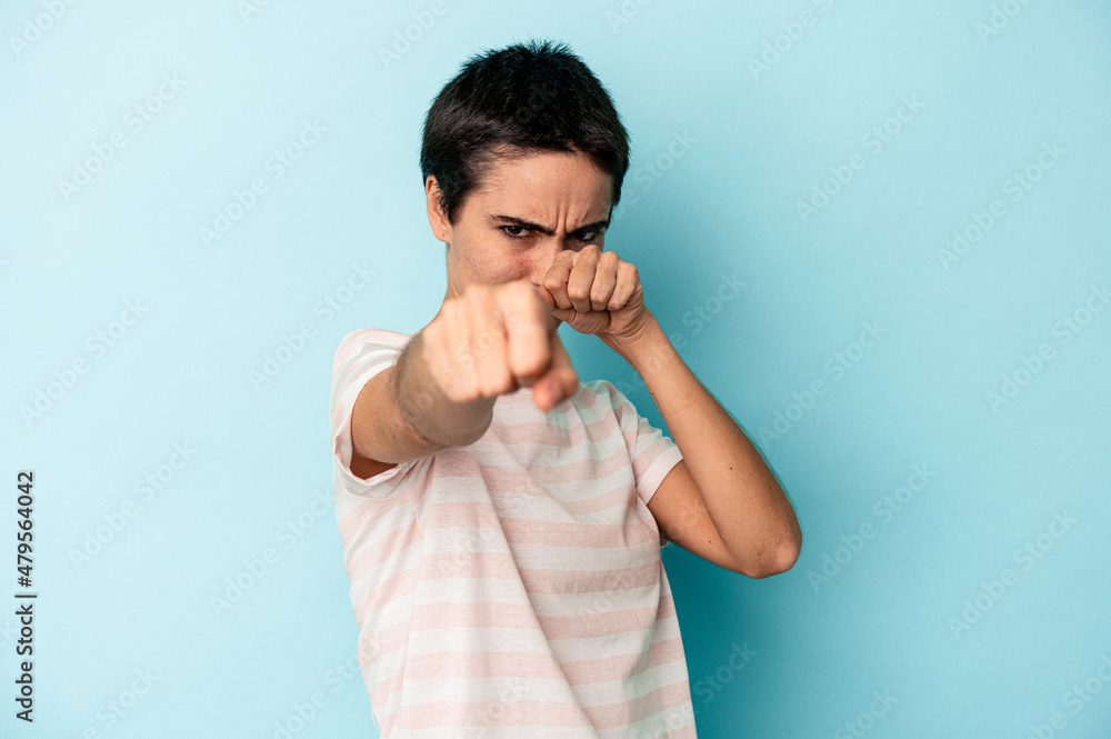 Young caucasian woman isolated on blue background throwing a punch, anger, fighting due to an argument, boxing. Young caucasian woman isolated on blue background throwing a punch, anger, fighting due to an argument, boxing.