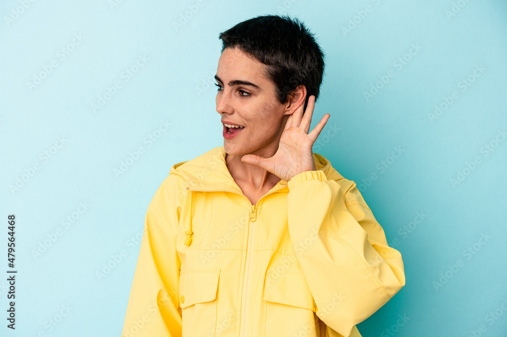 Young caucasian woman isolated on blue background trying to listening a gossip. Young caucasian woman isolated on blue background trying to listening a gossip.