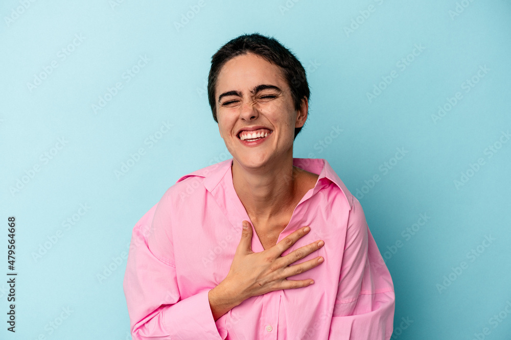 Obraz premium Young caucasian woman isolated on blue background laughs out loudly keeping hand on chest.