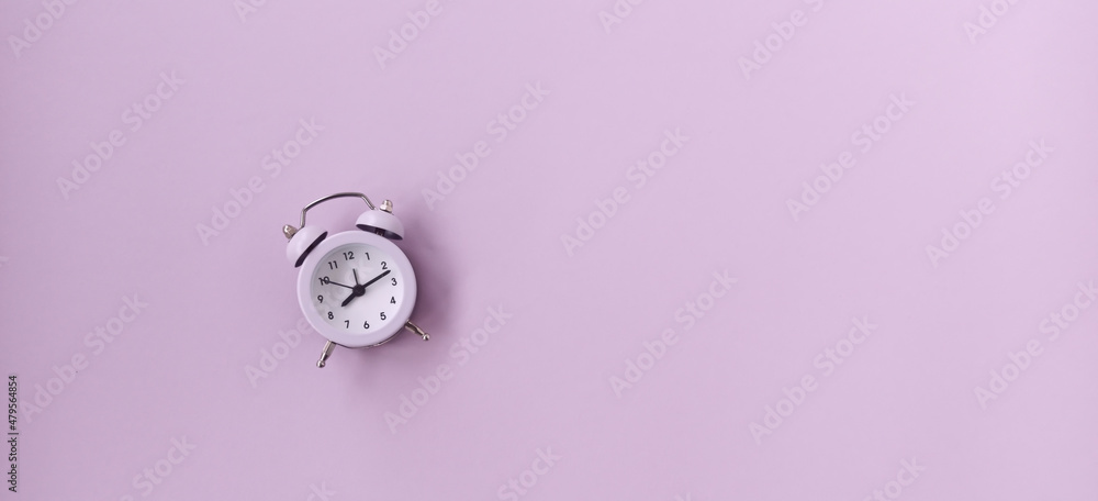 A white alarm clock on a pink background with a good morning wish. 