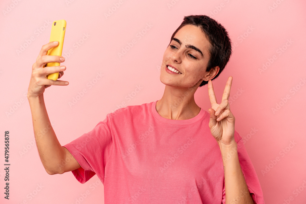 Young caucasian woman holding mobile phone isolated on pink background